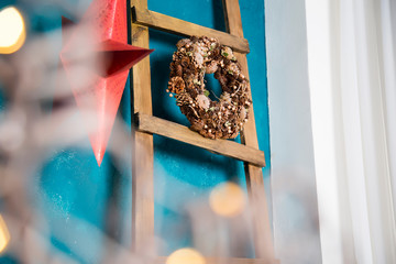 Wreath from cones hangs on the ladder put to a blue wall