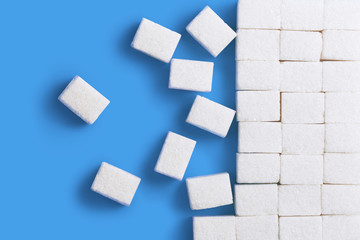 White sugar cubes, isolated on bluebackground, view from above