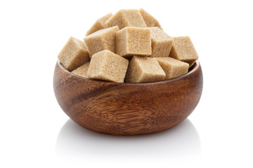 Brown sugar cubes in a brown wooden bowl, isolated on white background