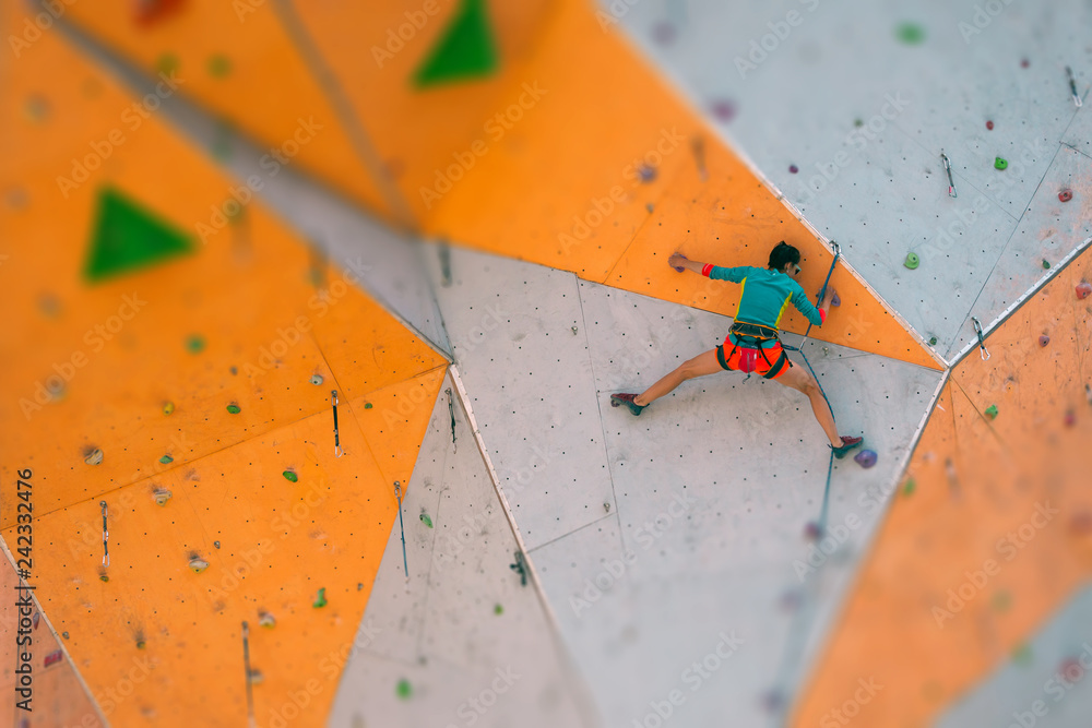 Wall mural A girl climbs a climbing wall.