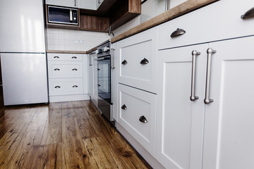 Fototapeta premium Luxury modern kitchen furniture in grey color and steel oven,fridge, sink, wooden tabletop. Gray cabinets in scandinavian style. Home renovation. Stylish kitchen interior design.