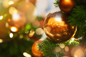 Close up of stylish Christmas tree toys and garland lights on branches.