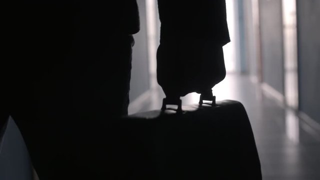 Close up view of hand of businessman carrying briefcase along dark corridor in office center
