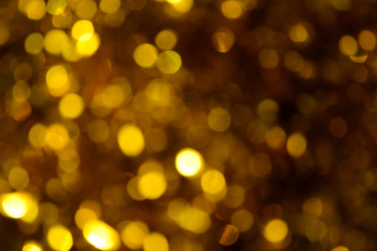 Bokeh. Holiday background. Christmas lights. Glitter. Defocused sparkles. New Year backdrop. Festive wallpaper. Blinks. Carnival. Tinsel. Bokeh retro style photo. Golden. Gold.