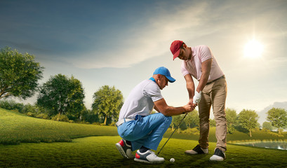 Male golf players on professional golf course. Golfer teaches to play golf