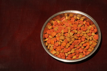 A bowl of dry cat pellets in a silver bowl with space for text on the left side.