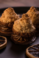 Few pieces of baked sweets on dark plate with orange rings