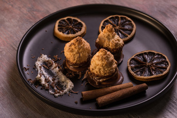 Few pieces of baked sweets on dark plate with orange rings