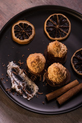 Few pieces of baked sweets on dark plate with orange rings