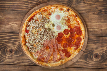 Fresh italian four seasons pizza on wooden background, top view