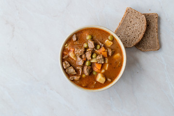 Tasty Hungarian Hot Goulash Soup Bograch or Gulas Lamb Meat Stew with Whole Grain Bread on Wooden...