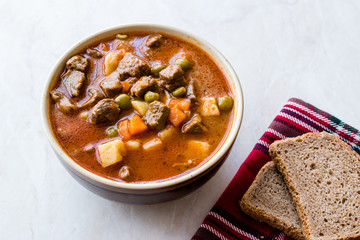 Tasty Hungarian Hot Goulash Soup Bograch or Gulas Lamb Meat Stew with Whole Grain Bread on Wooden Surface at Restaurant. Traditional Food.