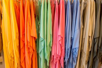 Fashion clothes on clothing rack - bright colorful closet. Close-up of rainbow color choice of trendy female wear on hangers in store closet or spring cleaning concept. Summer home wardrobe.