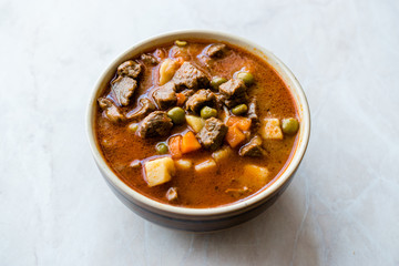 Tasty Hungarian Hot Goulash Soup Bograch or Gulas Lamb Meat Stew with Whole Grain Bread on Wooden Surface at Restaurant. Traditional Food.