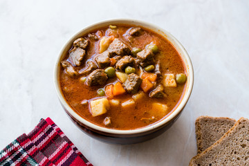 Tasty Hungarian Hot Goulash Soup Bograch or Gulas Lamb Meat Stew with Whole Grain Bread on Wooden Surface at Restaurant. Traditional Food.