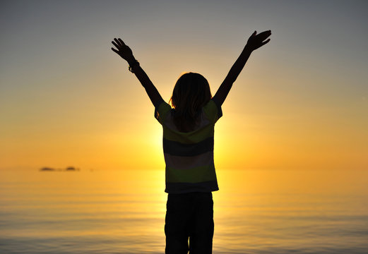 Little boy standing at sea on sunset