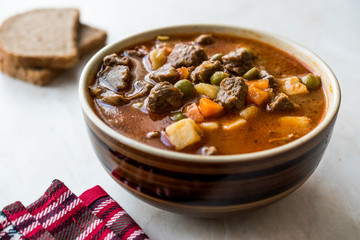 Tasty Hungarian Hot Goulash Soup Bograch or Gulas Lamb Meat Stew with Whole Grain Bread on Wooden Surface at Restaurant. Traditional Food.