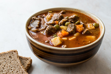 Tasty Hungarian Hot Goulash Soup Bograch or Gulas Lamb Meat Stew with Whole Grain Bread on Wooden...