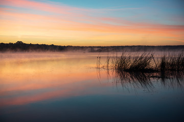 colorful misty sunset on the river in summer