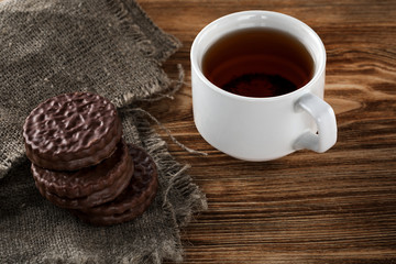 Chocolate chip cookies and a mug of tea on a white wooden table.