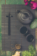 Asian food background - tea and chopsticks on dark rustic background.
