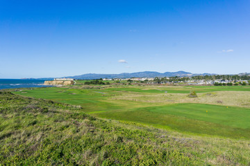 Golf course on the cliffs of the pacific ocean coast, resort and villas in the background, Half Moon Bay, California