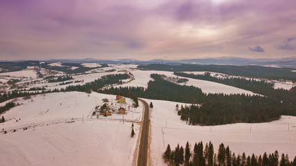 Aerial rural view of road passing to horizon. Winter snowy mountain landscape
