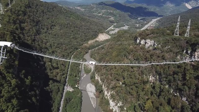 Sochi, Russia - NOVEMBER 20, 2018: SKYPARK AJ Hackett Sochi , Sochi National Park, Ahshtyrskaya gorge in Mzymta river valley. Crowd of visitors are walking along most long suspension bridge, evening