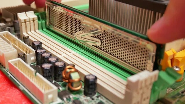 Hand installing random access memory RAM into motherboard