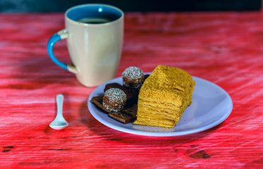 Puff cake, chocolates and coffee mug on vintage wooden background.