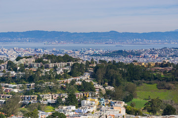 Aerial views of residential areas of San Francisco, San Francisco bay, Oakland and industrial areas in the background, California