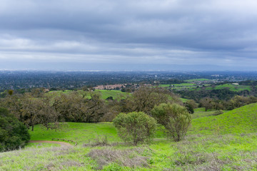 Fototapeta na wymiar Meadow and hills on a cloudy and rainy day in Rancho San Antonio county park; San Jose and Cupertino in the background, south San Francisco bay, California