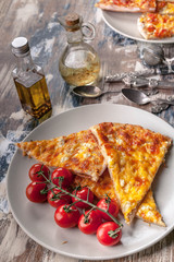 Tasty pizza and cherry tomatoes on a plate on a wooden table. Vertical shot. Mediterranean Kitchen