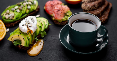 breakfast with avocado, sesame, grapefruit, orange, egg, coffee on a concrete black background