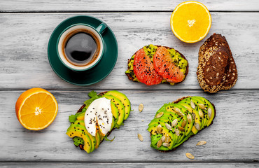 breakfast with avocado, sesame, orange, egg, coffee on a wooden background