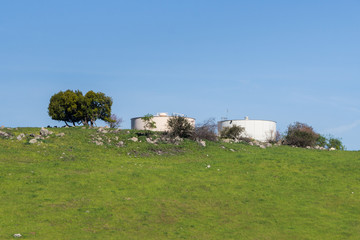 Obraz premium Large, round water tanks on top of a hill on a blue sky background, California