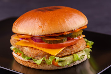 Chicken burger with cucumbers and tomatoes, lettuce leaves and cheese