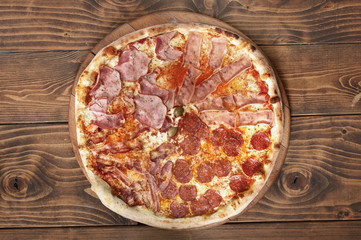Fresh italian four seasons pizza on wooden background, top view