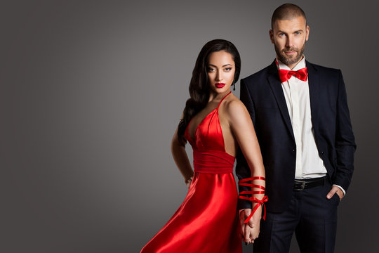 Fashion Couple, Woman and Man Arms Bounded by Ribbon, Models Studio Portrait in Red Dress and Black Suit