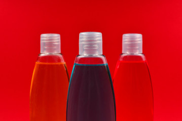 Four plastic bottles with liquid yellow, green and red soap.