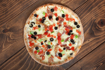 Fresh italian pizza with bacon and olives on wooden background