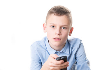 Boy with a blue shirt holds a remote control in his hand and tries to operate it