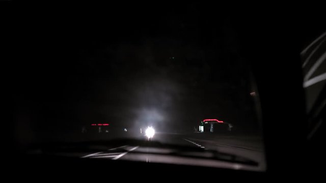 Car rides on the night road. Inside view. Dashboard, radio, DVR. Overtaking. Oncoming cars blind eyes. Headlights light the way. Road signs and markings. Traffic Laws. Track out of town