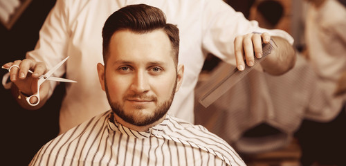 Man with fashionable haircut and styling in men hair salon, free space for text on right