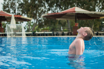 Happy teen boy in pool at aqua park
