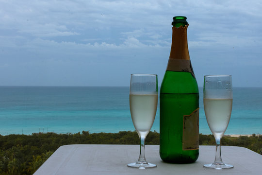 Botella de champ&aacute;n con par de copas y el mar de fondo