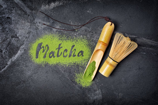 Lettering from green matcha tea with bamboo scoop and whisk on black background