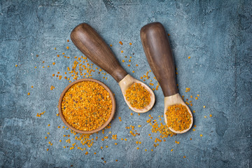Natural product bee pollen in rustic spoons and wooden bowl