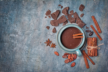 Chocolat chaud fait maison dans une tasse en céramique avec des épices, des morceaux de chocolat et des fèves de cacao