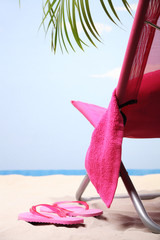 Beach chair under a green palm on a white sand beach
